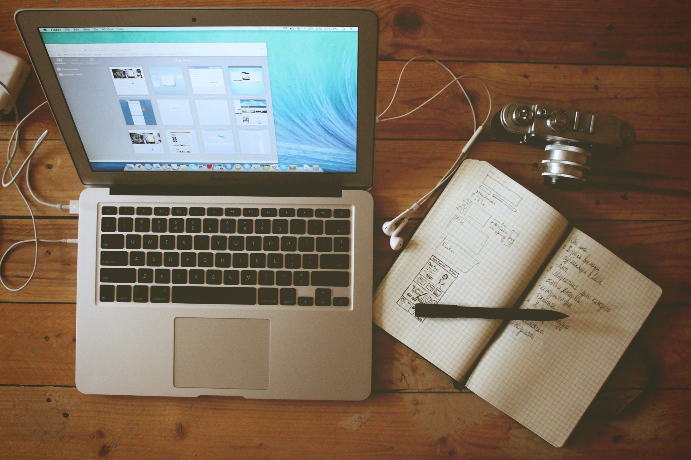 laptop, notebook, and camera on desk
