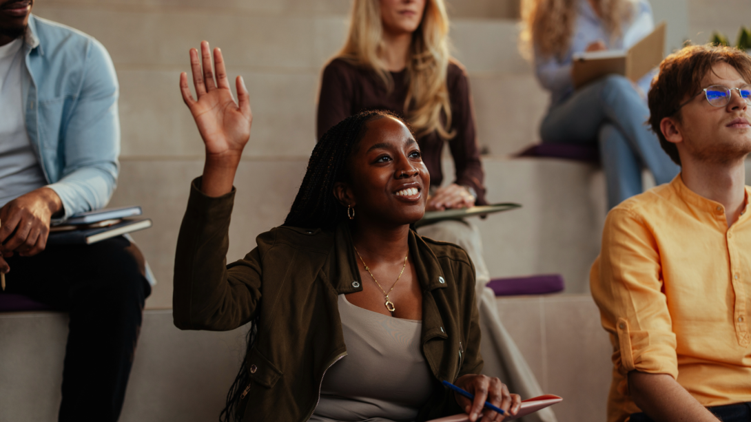University student raising hand in lecture hall asking question